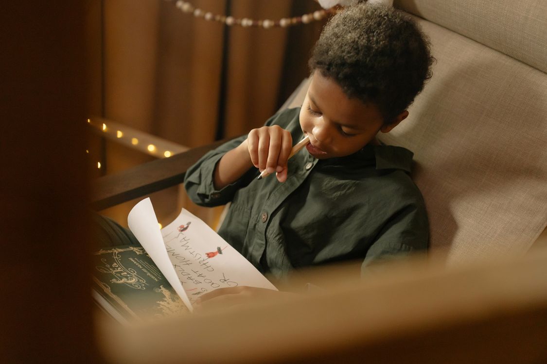 Niño escribiendo su carta a los Reyes Magos con lápices de colores
