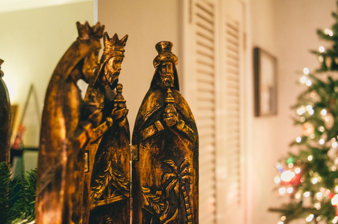 Figuras talladas de los tres Reyes Magos junto al árbol de Navidad