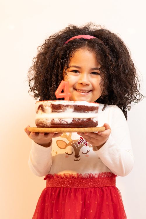 Niña sujetando su tarta con una vela de cumpleaños
