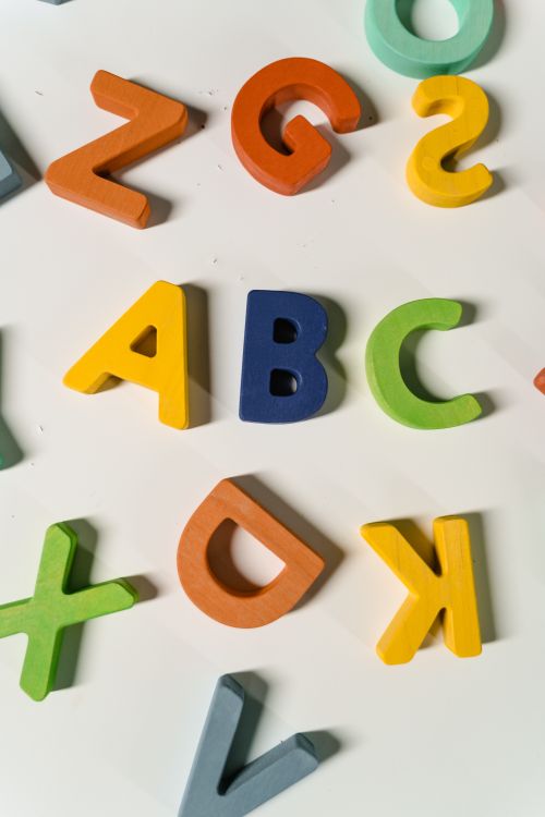 Letras de madera de colores repartidas sobre una superficie blanca